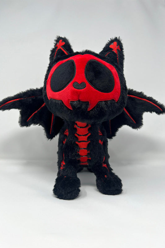 Black and red plush cat toy with bat wings on a white background