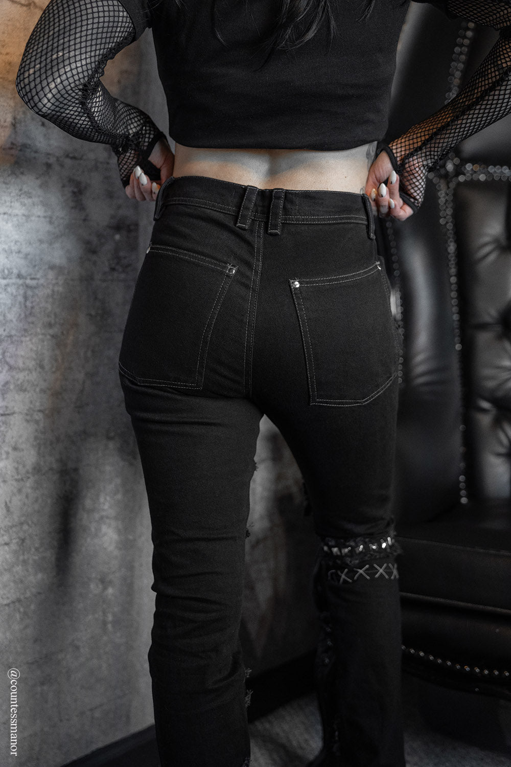 gothic skinny jeans with shredded details, distressing, a striped patch, and a skull patch
