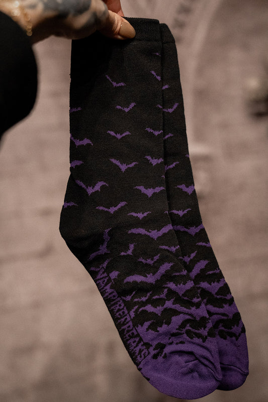 Black socks with purple bat patterns on a dark surface