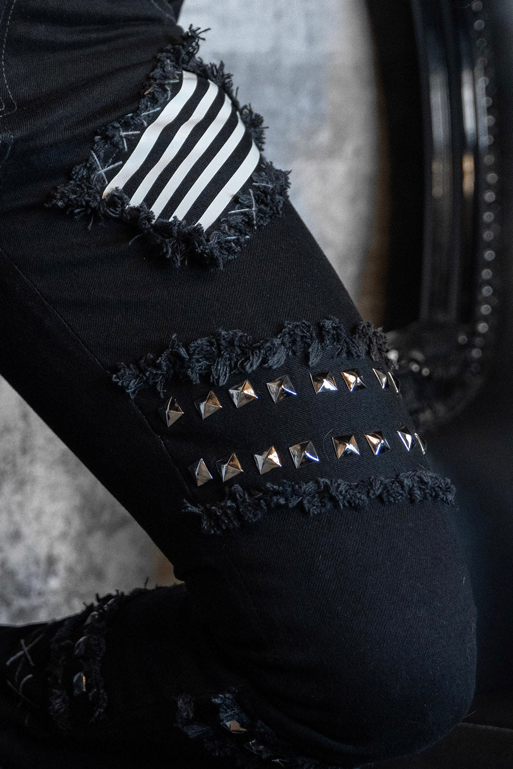 stitched pyramid studded scene skinny jean pants with a striped black and white patch 