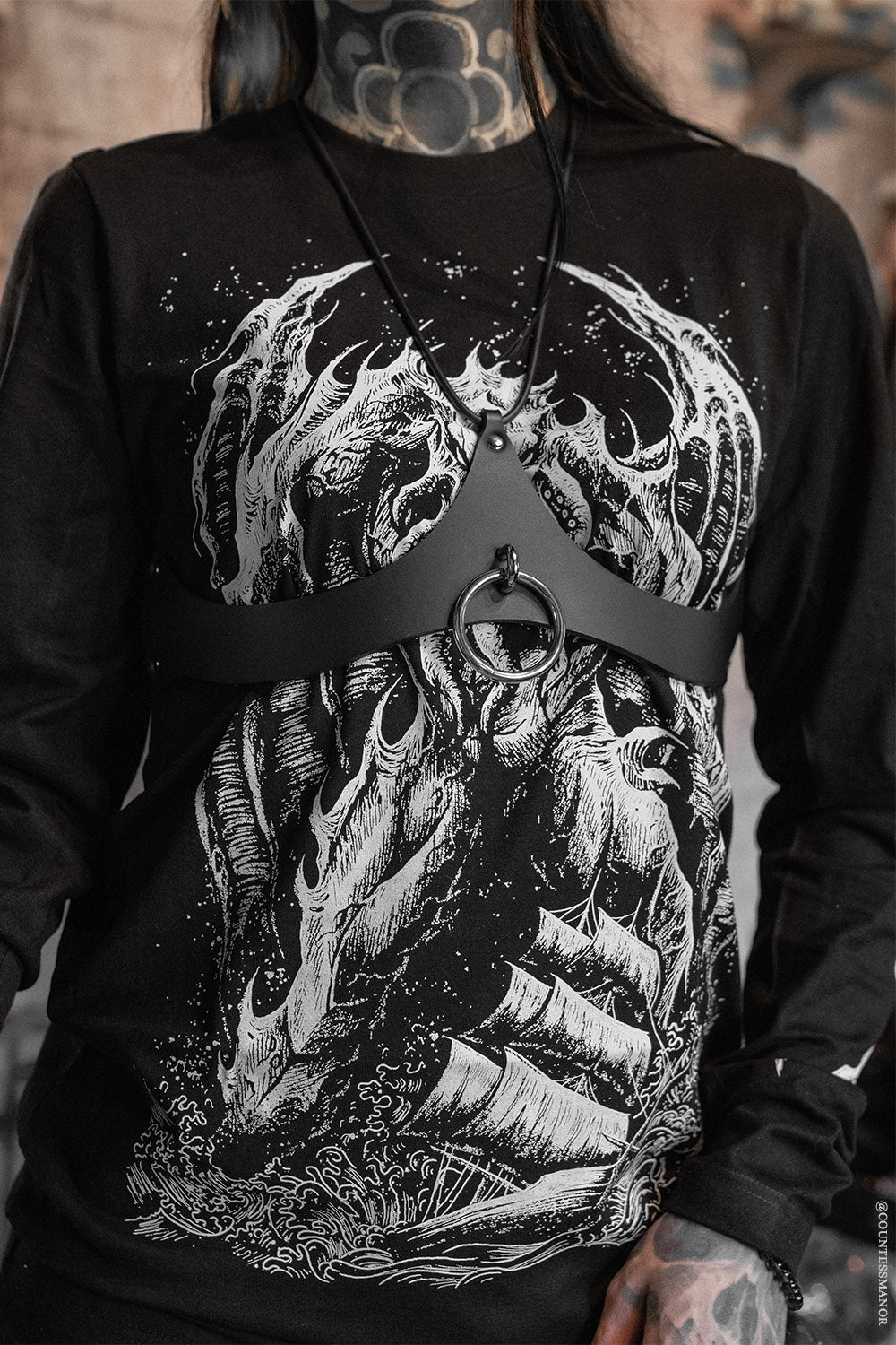 goth girl wearing a tattoo inspired t0shirt with a harness 