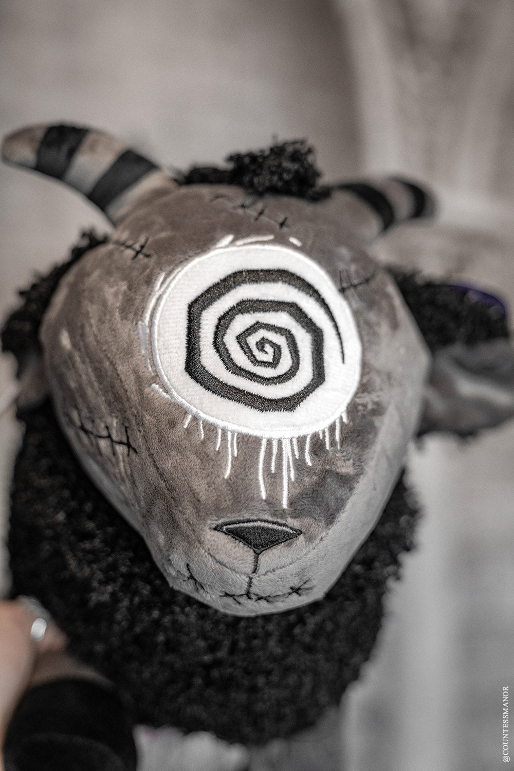 goth sheep plush toy with spiral eye and striped horns 